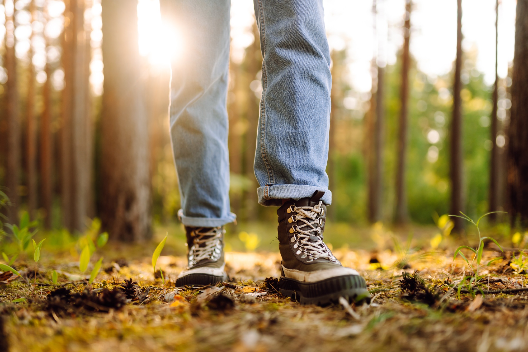 Feet of an adult wearing boots to travel walking in the forest. Feet walking in outdoor nature