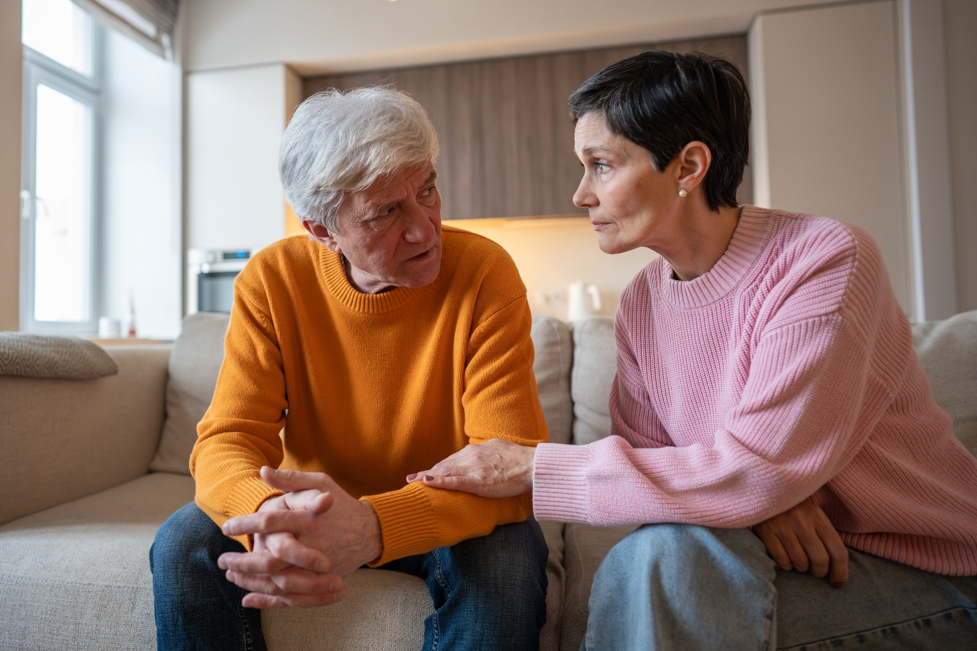 Brain Tumour Warning Signs Loving wife holding hands with distressed serious husband on couch offering emotional support